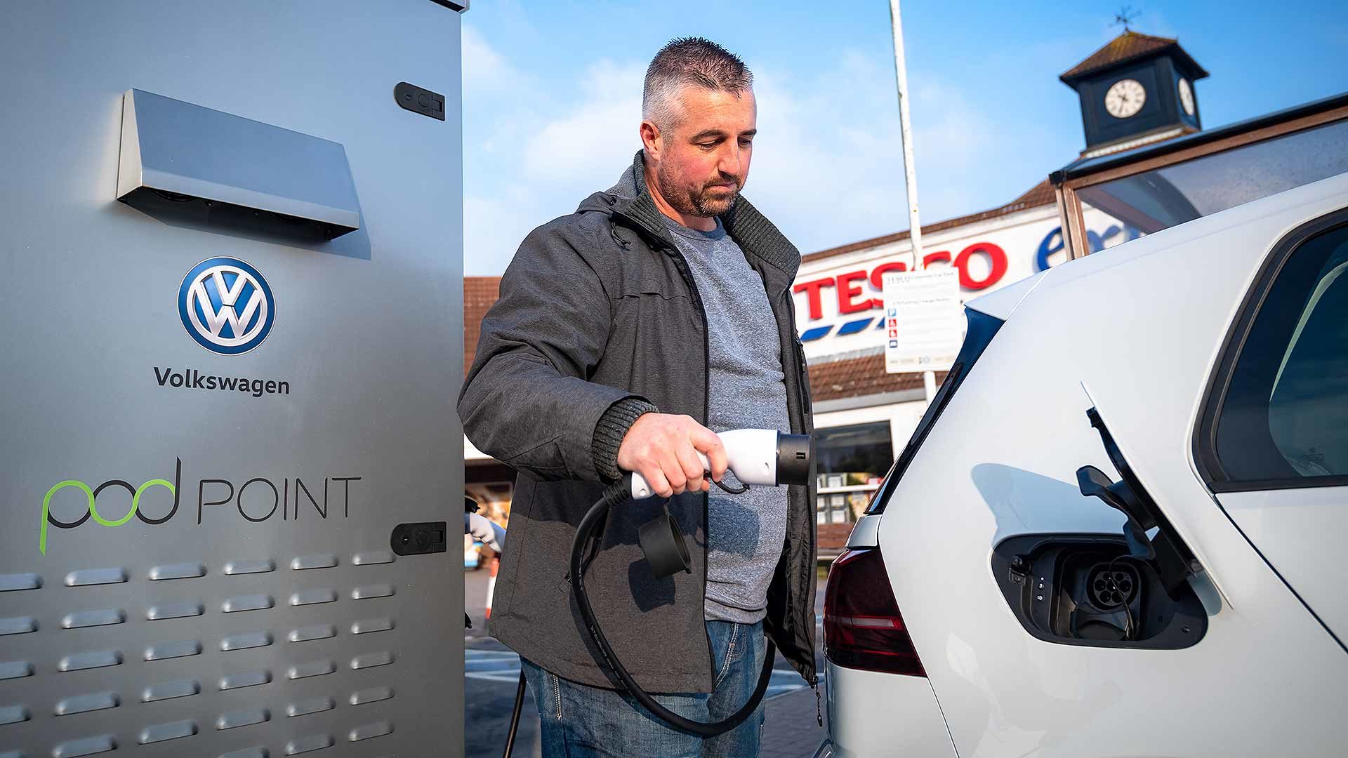 Man charging EV at a supermarket